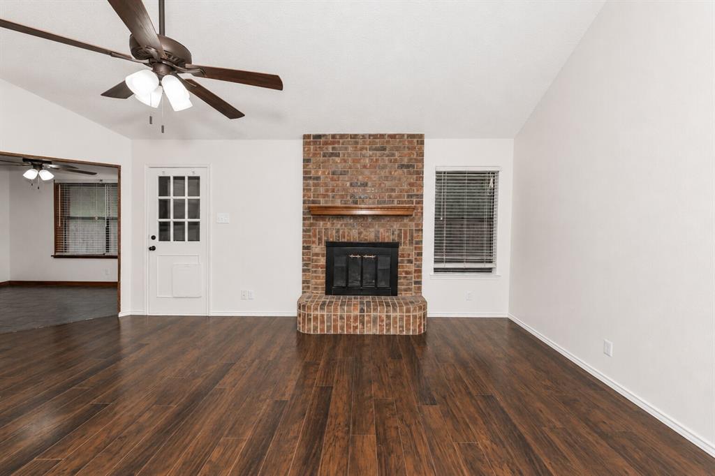 1001 Rosebud Drive Azle, TX 76020 - Photo 11 of 36 Living area featuring wood-finish flooring, a brick fireplace with a wood mantel, and vaulted ceilings with a ceiling fan
