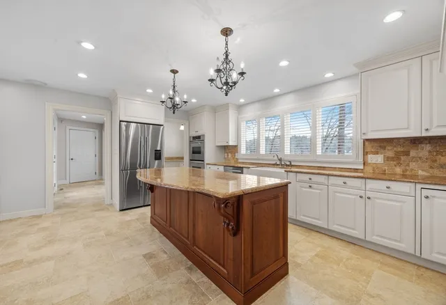 a kitchen with kitchen island granite countertop a sink and refrigerator