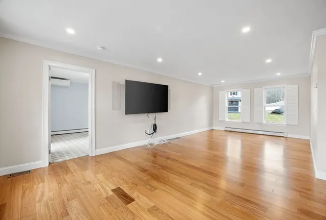 a view of empty room with wooden floor and windows