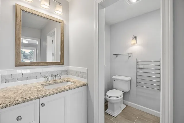 a bathroom with a granite countertop sink a toilet and a mirror