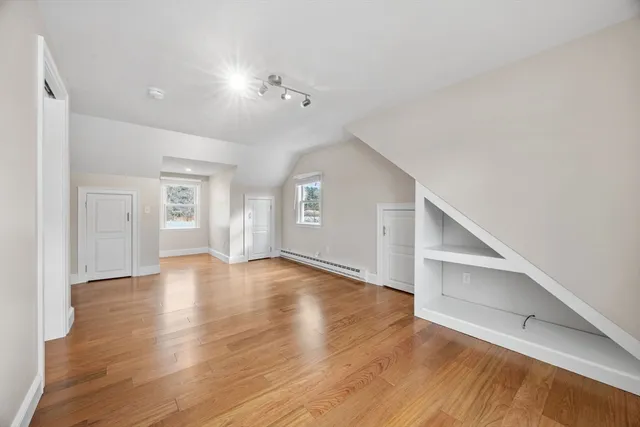 a view of an empty room with wooden floor and kitchen