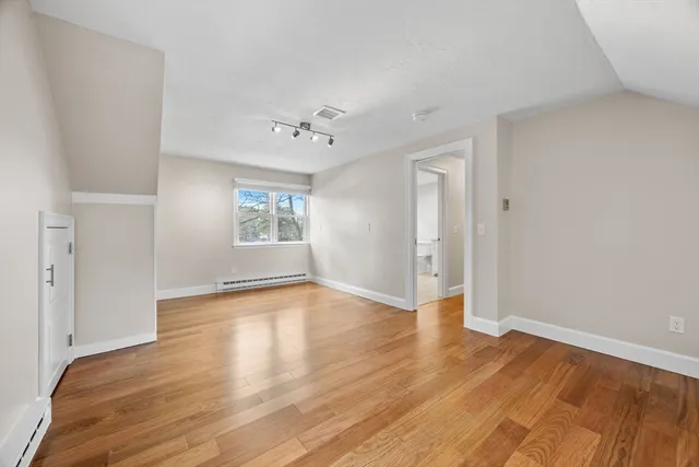 a view of an empty room with a window and wooden floor