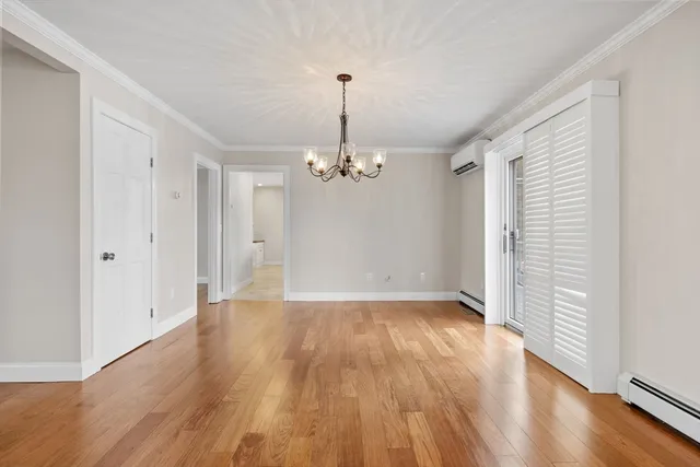 an empty room with wooden floor chandelier and windows