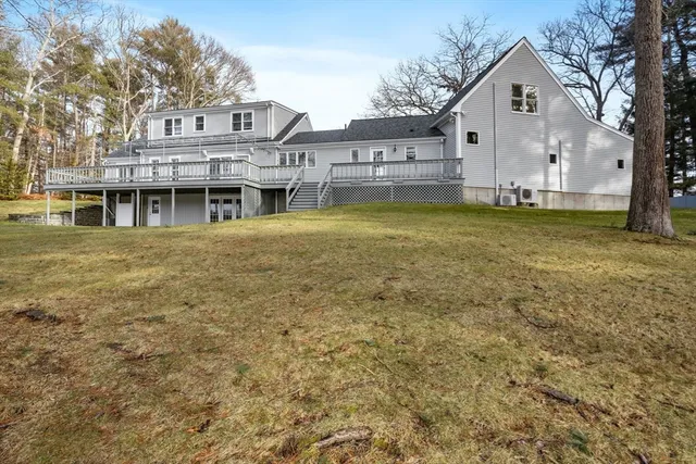 a view of a white house next to a big yard with large trees