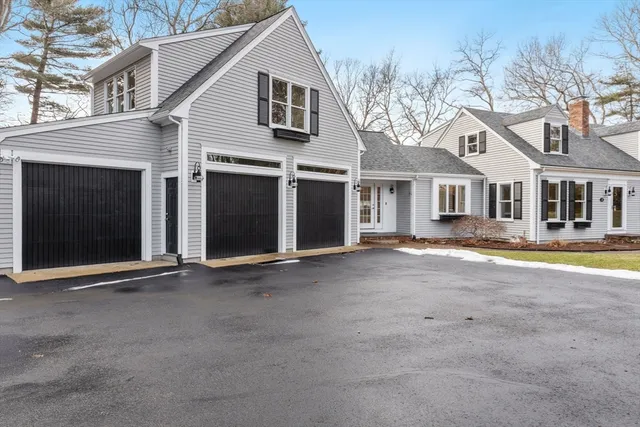a view of a white house with large windows next to a road
