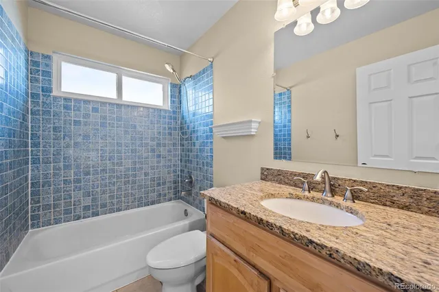 a bathroom with a granite countertop sink a toilet and bathtub