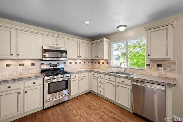 a kitchen with cabinets stainless steel appliances a sink and a window
