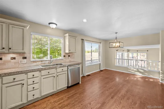 a open kitchen with granite countertop a large window a sink and white appliances