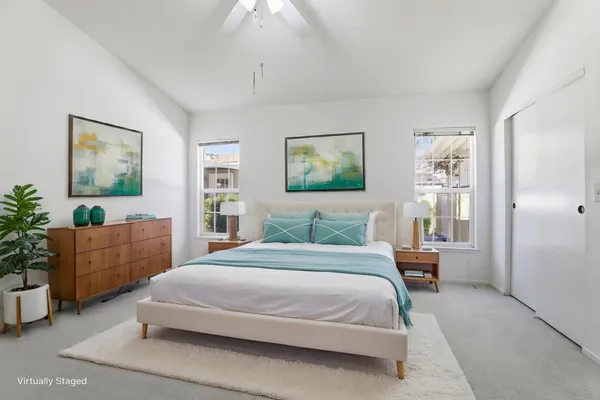 a bedroom with a large bed a couch and paintings on the wall