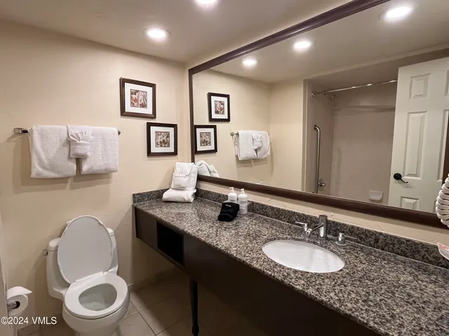 a bathroom with a granite countertop toilet a sink and a mirror
