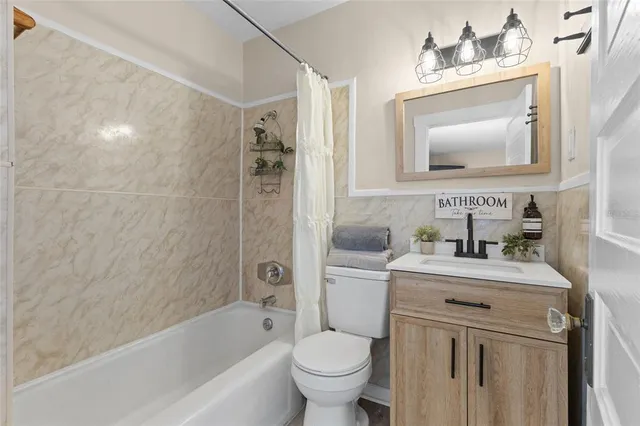 a bathroom with a toilet sink vanity tub and mirror