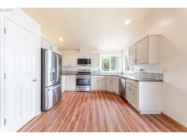 a kitchen with a refrigerator a sink dishwasher with a dining table and wooden floor