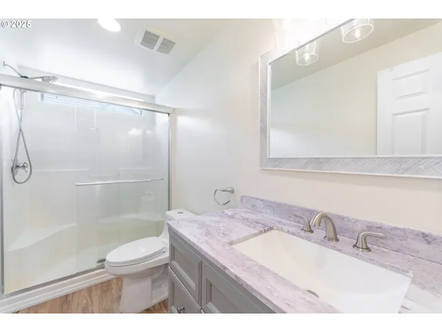 a bathroom with a granite countertop sink toilet a mirror and shower