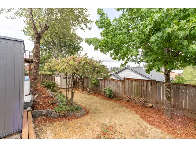 a backyard of a house with large trees and outdoor seating
