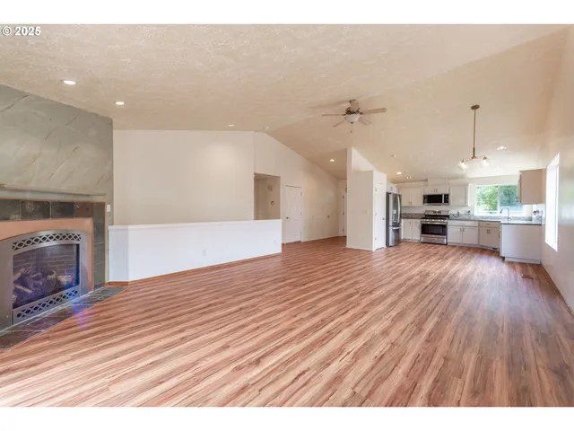 an empty room with wooden floor fireplace and windows