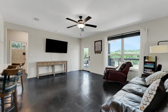 a living room with furniture a ceiling fan and a large window