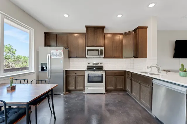a kitchen with stainless steel appliances a stove a sink refrigerator and a microwave