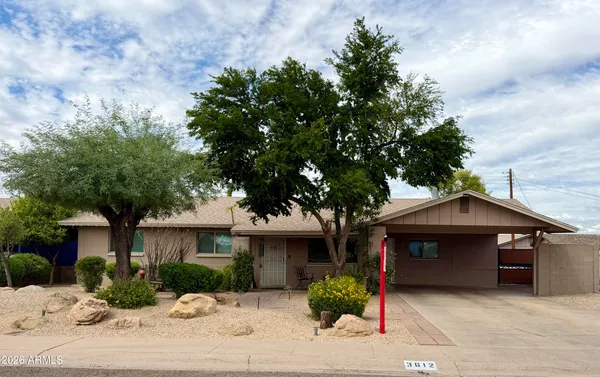 a front view of a house with a garden and tree