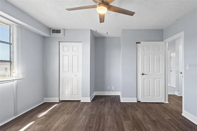 an empty room with wooden floor cabinet and windows
