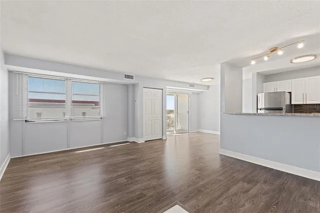 a view of a kitchen with a refrigerator and wooden floor