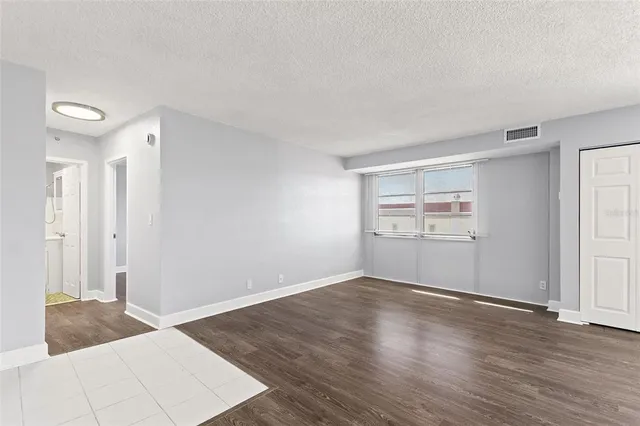 an empty room with wooden floor cabinet and windows