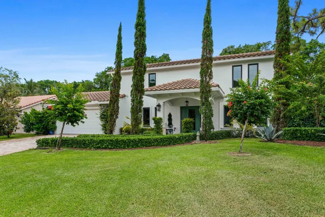 a view of a white house with a big yard and potted plants
