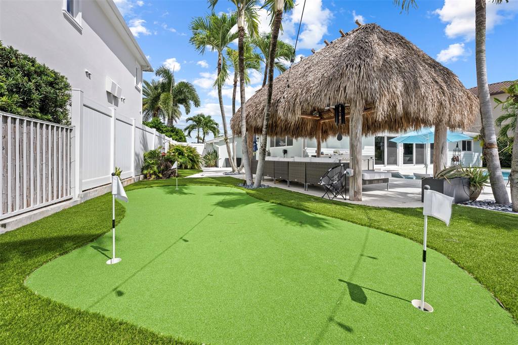 2330 Northeast 35th Street Lighthouse Point, FL 33064 - Photo 36 of 71 a backyard of a house with table and chairs under an umbrella