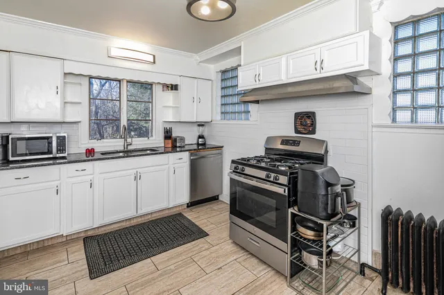a kitchen with stainless steel appliances a sink a stove a refrigerator cabinets and a window