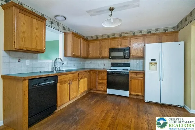 a kitchen with granite countertop wooden floors stainless steel appliances and a counter space