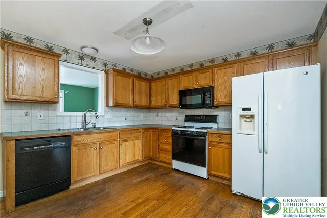 a kitchen with stainless steel appliances granite countertop a stove top oven a sink dishwasher a refrigerator and a microwave oven with wooden floor