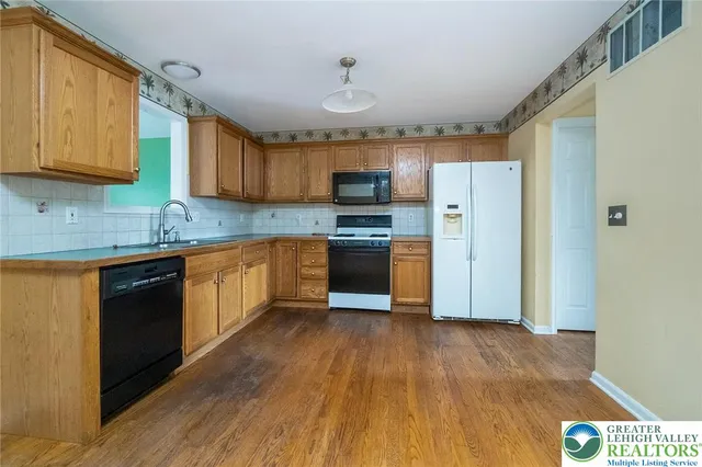 a kitchen with stainless steel appliances granite countertop a stove top oven a sink dishwasher and a refrigerator with wooden floor