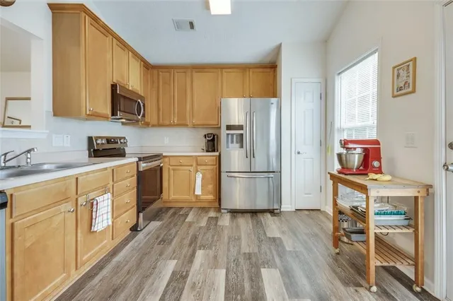 a kitchen with stainless steel appliances granite countertop a stove top oven a refrigerator and white cabinets with wooden floors