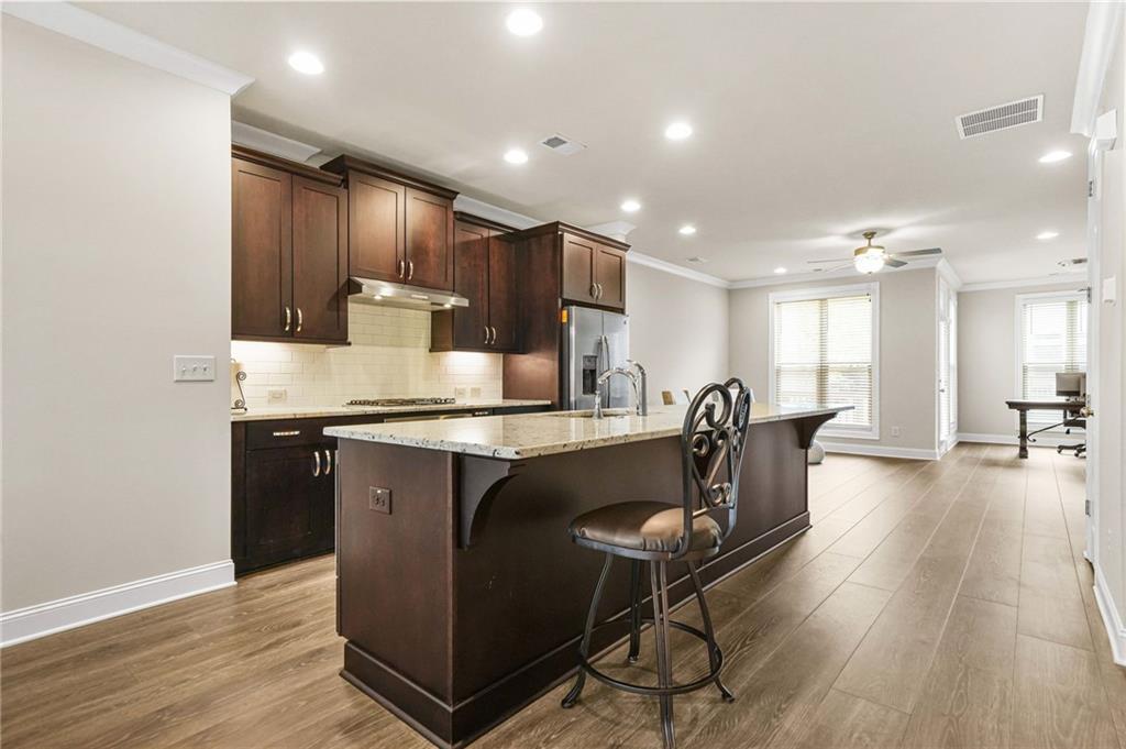 2207 Parkside Gln View Duluth, GA 30097 - Photo 3 of 41 a kitchen with kitchen island granite countertop wooden floors and wooden cabinets
