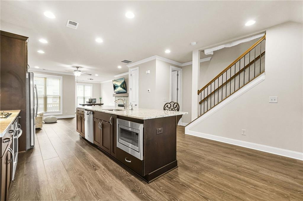 2207 Parkside Gln View Duluth, GA 30097 - Photo 5 of 41 a kitchen with stainless steel appliances kitchen island wooden floors granite top and stove