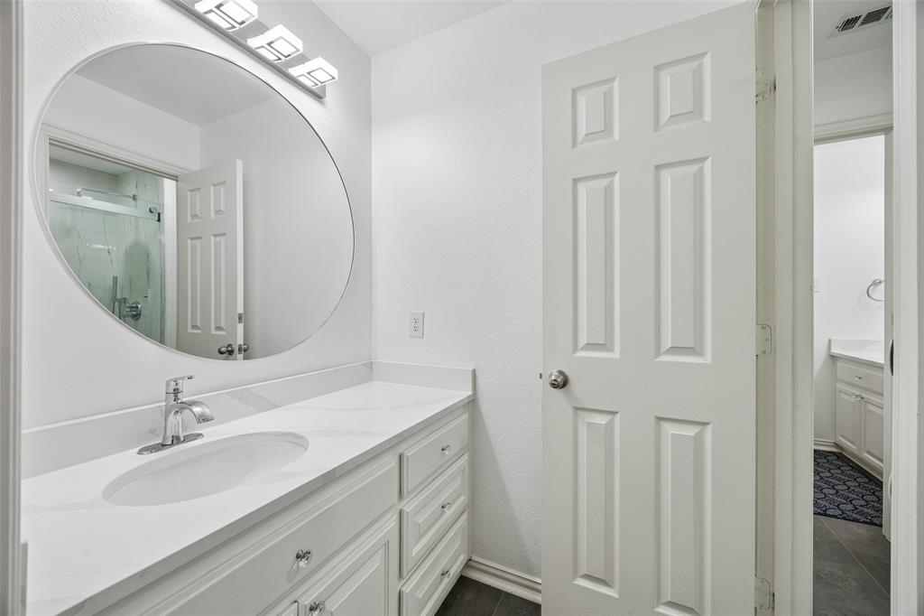 2865 Ridge View Road Frisco, TX 75034 - Photo 30 of 38 White paneled door opening to a vanity area with a chrome faucet, oval sink, and a circular mirror