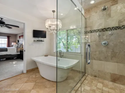 a spacious bathroom with a tub a mirror and a shower
