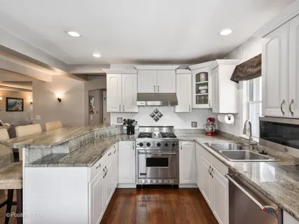 a kitchen with granite countertop stainless steel appliances a sink stove and cabinets