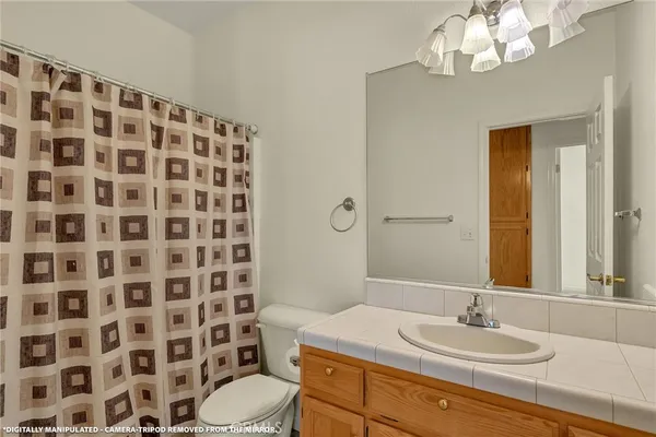 a bathroom with a sink a toilet a mirror and shower curtain
