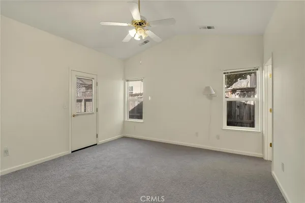 an empty room with chandelier fan and windows