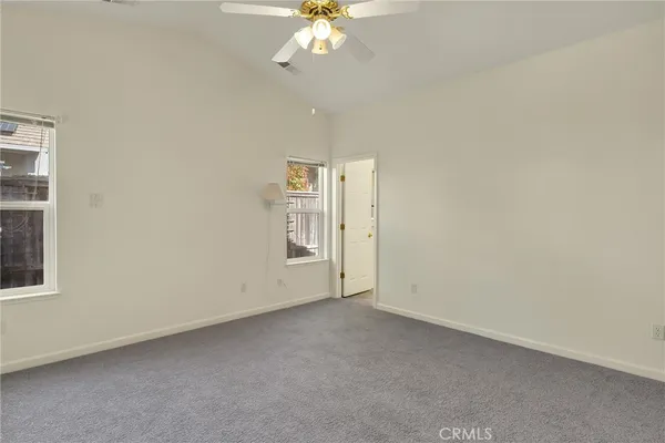an empty room with a chandelier fan and windows