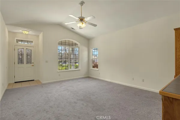 an empty room with chandelier fan and windows