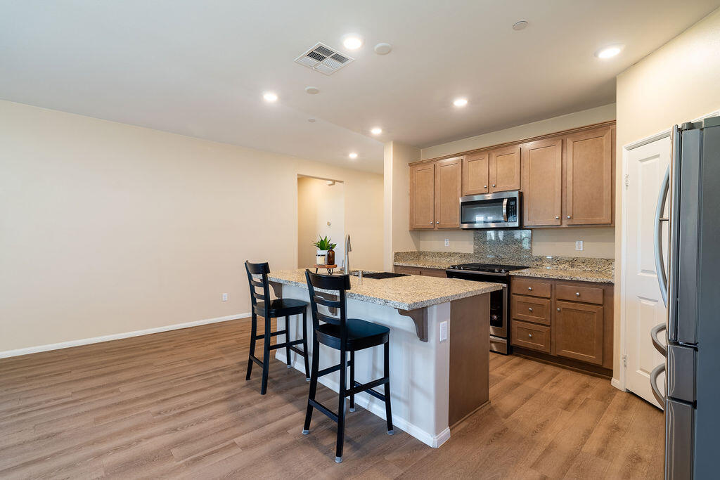 67470 Rio Naches Road Cathedral City, CA 92234 - Photo 5 of 32 a kitchen with stainless steel appliances granite countertop a white cabinets and wooden floor