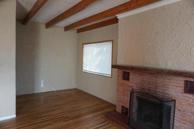 44822 Genoa Avenue Lancaster, CA 93534 - Photo 4 of 27 a view of an empty room with wooden floor and a fireplace