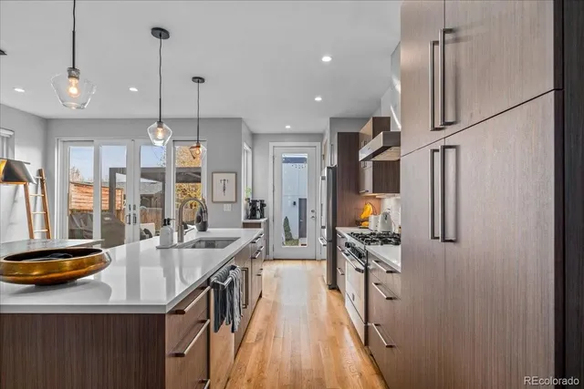 a kitchen with stainless steel appliances granite countertop a refrigerator a sink dishwasher a stove and a dining table with wooden floor