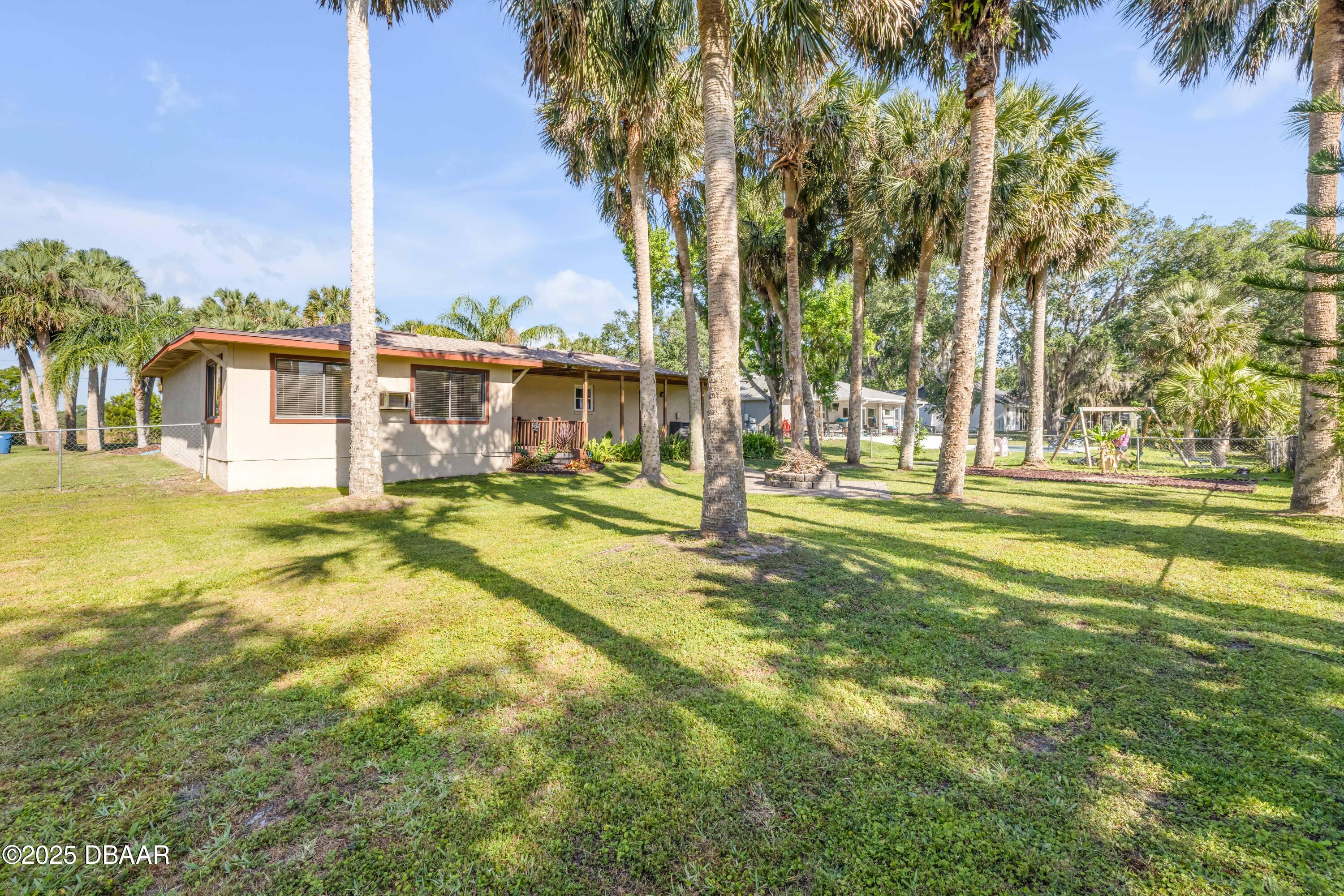 1617 Hontoon Road DeLand, FL 32720 - Photo 36 of 43 a view of a swimming pool with a lawn chairs under palm trees