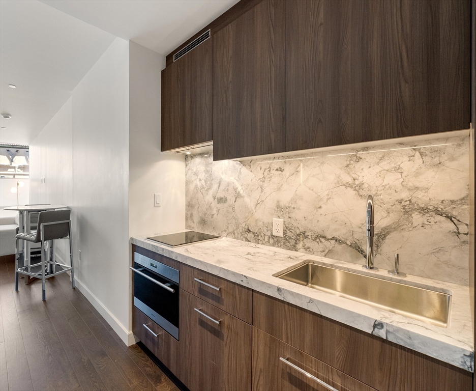 40 Trinity Place, Unit 1518 Boston, MA 02116 - Photo 4 of 25 a kitchen with granite countertop wooden cabinets and sink