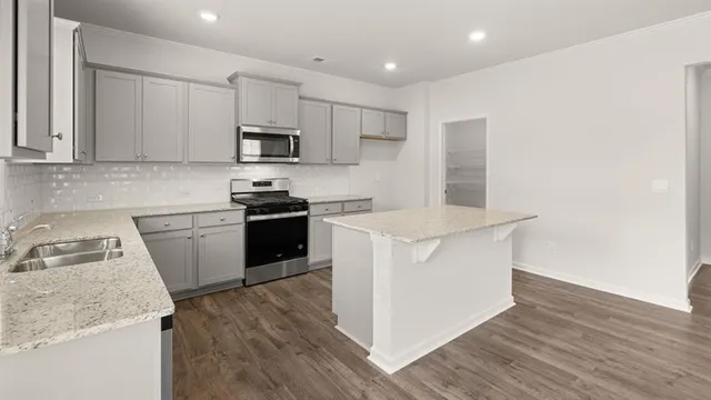 a kitchen with a sink dishwasher a stove and white cabinets with wooden floor