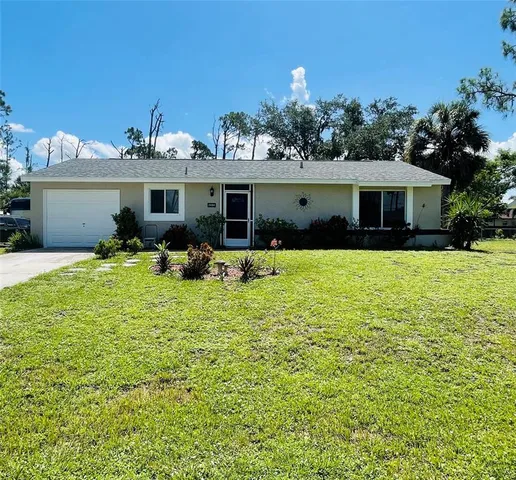 a front view of house with yard and trees in the background