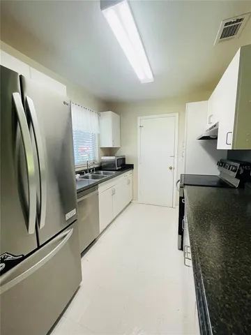 a kitchen with stainless steel appliances a refrigerator sink and white cabinets