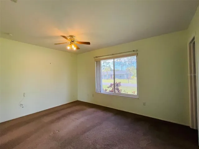 an empty room with a window and a ceiling fan